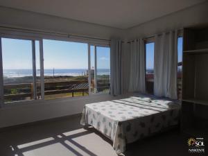 um quarto com uma cama e vista para o oceano em Pousada Moradas do Sol Nascente em Passo de Torres