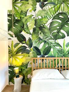 una camera da letto con un murale di foglie sul muro di Casa Cannoni - Delizioso Appartamento Fronte Mare vista Stretto di Messina a Messina