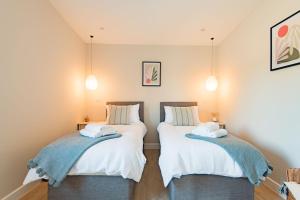 two beds in a room with white sheets at Lacton Manor Barns by Bloom Stays in Ashford