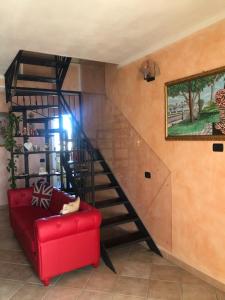 a red couch in a room with a spiral staircase at B&B San Giorgio in Traversetolo