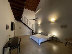 a bedroom with a white bed and a staircase at Karakali Boutique Hotel in Mompos