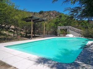 a large blue swimming pool with an umbrella at Kailash Posada in San Marcos Sierras