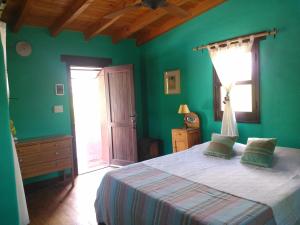 Dormitorio verde con cama y ventana en Kailash Posada en San Marcos Sierras