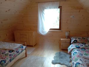 pokój z łóżkiem i oknem w drewnianym domku w obiekcie Markowa Chata w Cisnej