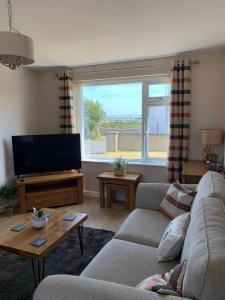 a living room with a couch and a flat screen tv at Two bedroom house with enclosed gardens and 2 car drive in Caeʼr-geiliog
