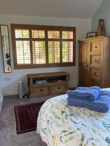 a bedroom with a bed and a dresser and windows at The Old Barn Annexe in West Runton