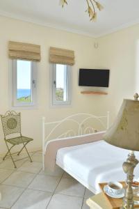 - une chambre avec un lit, une chaise et une télévision dans l'établissement Andros Homes Sea Side Apartment & Studio, à Gavrio