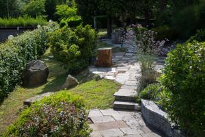 a garden with a stone path with flowers and bushes at Hotel San Francesco in Borgomanero