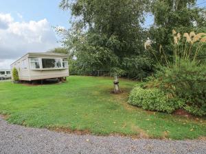 a caravan in a yard with trees and grass at 8 Old Orchard in Much Wenlock