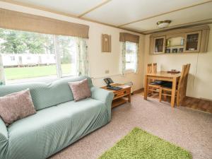 a living room with a blue couch and a desk at 8 Old Orchard in Much Wenlock