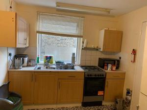 cocina con fregadero, fogones y ventana en Amazing and Lovely 2- Bedroom First Floor Flat en Londres