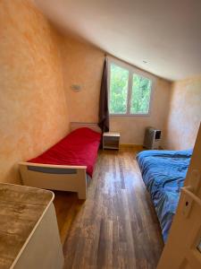 - une chambre avec un lit rouge et une fenêtre dans l'établissement Maison située au Val de Baubère, petite vallée à coté du village de Seix, à Seix