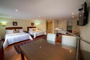 Habitación de hotel con 2 camas y mesa en Hotel Portón Bogota, en Bogotá