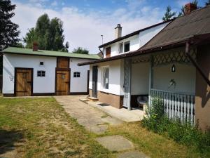 a white house with a wooden door next to a yard at Sielanka Aleksandria in Aleksandria