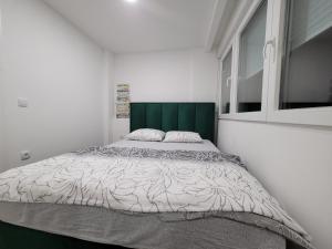 Schlafzimmer mit einem großen Bett mit einem grünen Kopfteil in der Unterkunft Stan m&s, Boulevard-centar grada in Banja Luka