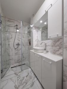 a white bathroom with a sink and a shower at Stan m&s, Boulevard-centar grada in Banja Luka