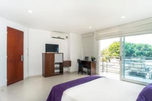 a bedroom with a bed and a desk and a window at Hotel Sol de Piedemonte in Yopal