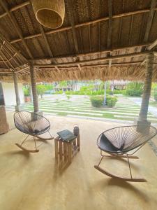 2 chaises et une table sous un toit de paille dans l'établissement Tay Beach Hotel Tayrona, à Buritaca