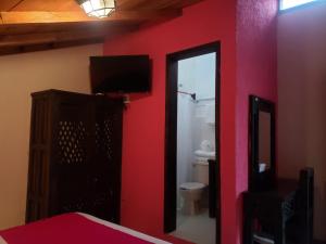 Habitación con pared roja y baño con aseo. en Hotel Antigua en San Cristóbal de Las Casas