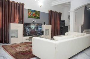 a living room with a white couch and a tv at Villa luxueuse - Odza - Yaoundé in Yaoundé