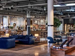 a lobby with blue couches and tables and a bar at Clarion Collection Hotel Tapetfabriken in Stockholm