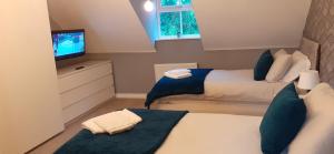a small bedroom with two beds and a television at Hawksworth House, Birmingham Near NEC, HS2, Jaguar Land Rover, Bear Grylls Centre, Resorts World and Birmingham airport with a garage and free allocated parking in Kingshurst