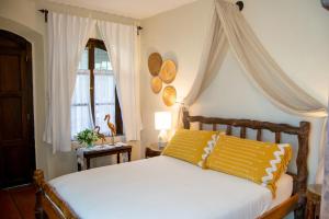 a bedroom with a white bed with a yellow pillow at Hotel La Villa Serena in Antigua Guatemala