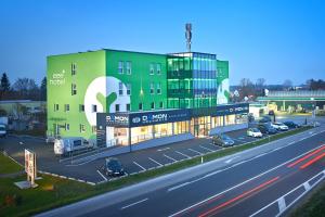 een groot groen gebouw met een parkeerplaats naast een snelweg bij eee Hotel Marchtrenk in Marchtrenk