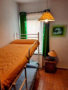 a bedroom with a bed with green curtains and a lamp at Casa Inma in Miraflores de la Sierra