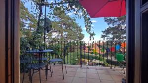 - un balcon avec des tables, des chaises et un parasol dans l'établissement Casa Inma, à Miraflores de la Sierra