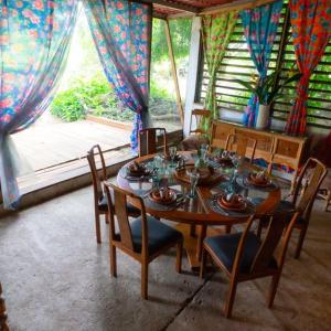 ein Esszimmer mit einem Tisch, Stühlen und einem Fenster in der Unterkunft Planta Glamp Farm in Santa María Huatulco
