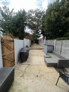 un patio con 2 panche e una recinzione di Modern 2 Bed House in Rainham, Kent - Central Location a Rainham