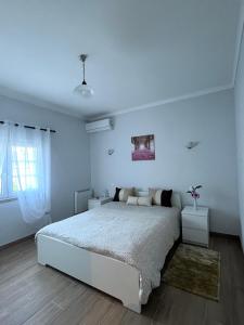 een witte slaapkamer met een groot bed en een raam bij Casa Pinto in Linhares de Cima