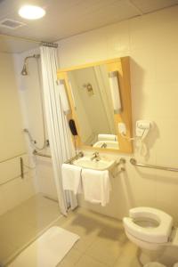 a bathroom with a toilet and a sink and a mirror at Ibis Sertaozinho in Sertãozinho