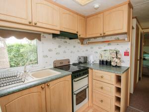 a kitchen with wooden cabinets and a sink at 9 Old Orchard in Much Wenlock