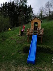 um parque infantil com um escorrega azul e uma pequena casa em Ferienwohnung Hofer em Pruggern