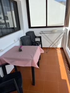 Casa La Orilla 2 في بلايا هوندا: طاولة وكراسي وردية في غرفة بها نوافذ