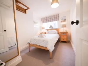 a small bedroom with a bed and a mirror at Padstow Escapes - Captains Cottage in Padstow