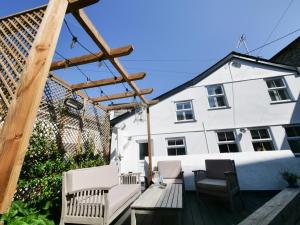 a patio with chairs and a wooden pergola at Padstow Escapes - Captains Cottage in Padstow