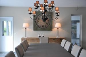 a dining room with a table and a clock on the wall at Petit coin de paradis in Somme-Leuze