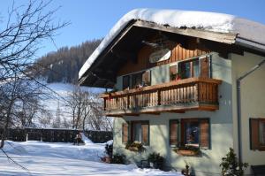 ein Haus mit einem Holzbalkon im Schnee in der Unterkunft Landhaus Glockner in Bruck an der Großglocknerstraße