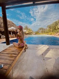 Ein kleines Mädchen auf einer Bank neben einem Pool in der Unterkunft Hotel Campestre Arboretto in Villavicencio