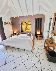 a bedroom with a large bed with a face painted on the wall at Résidence Adam et Eve in Orient Bay