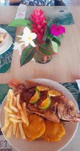a plate of fish and french fries and a bowl of flowers at Hotel Campestre Arboretto in Villavicencio