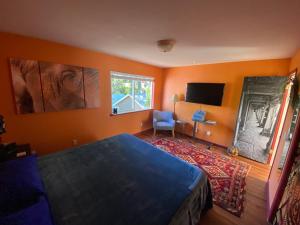 a bedroom with orange walls and a bed and a tv at My Big Art Project in Santa Rosa