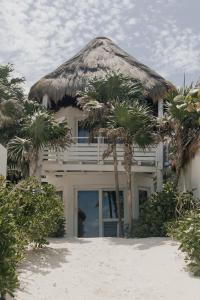 a house with a thatched roof and palm trees at Tuup Oceanfront in Tulum