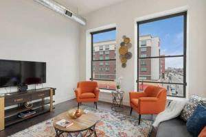 a living room with two orange chairs and a television at Flats-King bd-Corner Unit in Newark