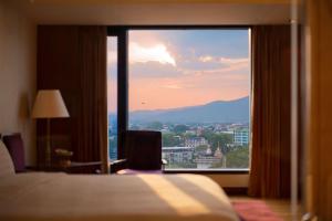 a bedroom with a view of a city from a window at Shangri-La Chiang Mai in Chiang Mai