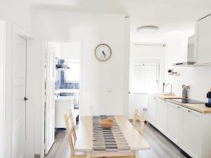 a white kitchen with a table and a clock on the wall at Caroline's in Vila do Bispo