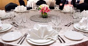 a table with white plates and glasses and a flower on it at The Elite Narasapura A Member of Radisson Individ in Narasapura